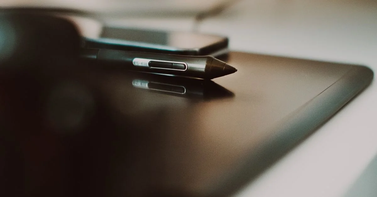 Gros plan d'un stylet et d'une tablette sur un bureau, parfait pour des thèmes créatifs et technologiques.