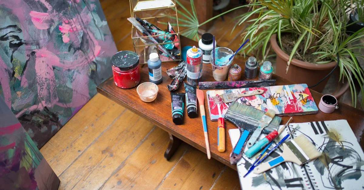 Fournitures d'art colorées et peintures abstraites dans un cadre confortable de studio d'artiste.