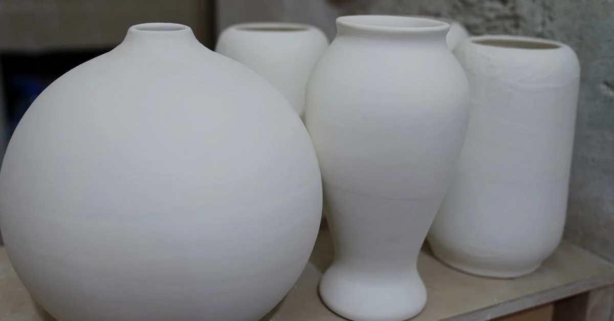 Vases en céramique blanche simples et élégants disposés sur une étagère, mettant en valeur un design minimaliste.