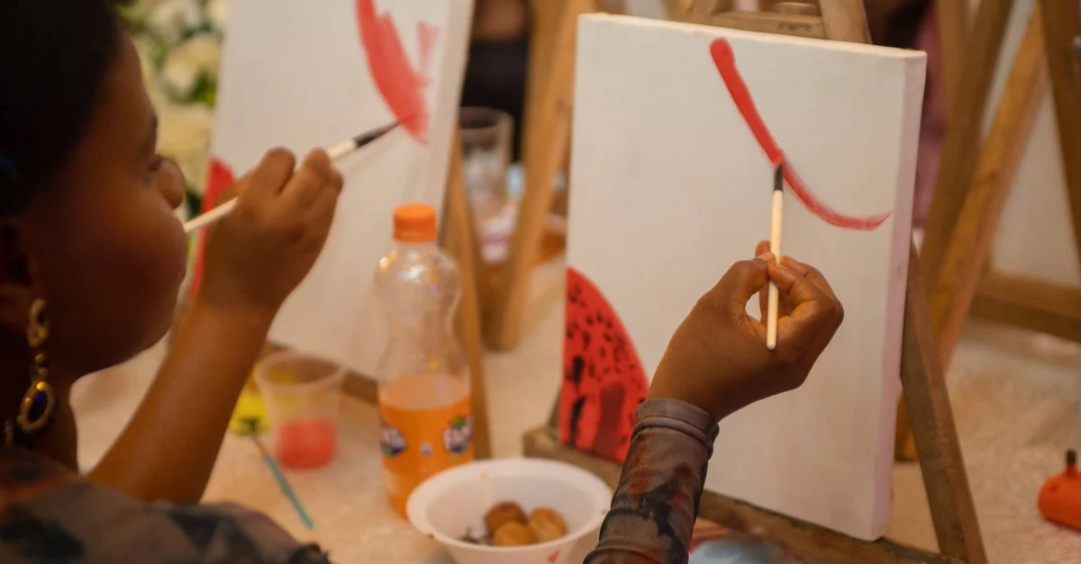 Des personnes de tous horizons apprécient une séance de peinture en groupe avec pinceaux et toiles.