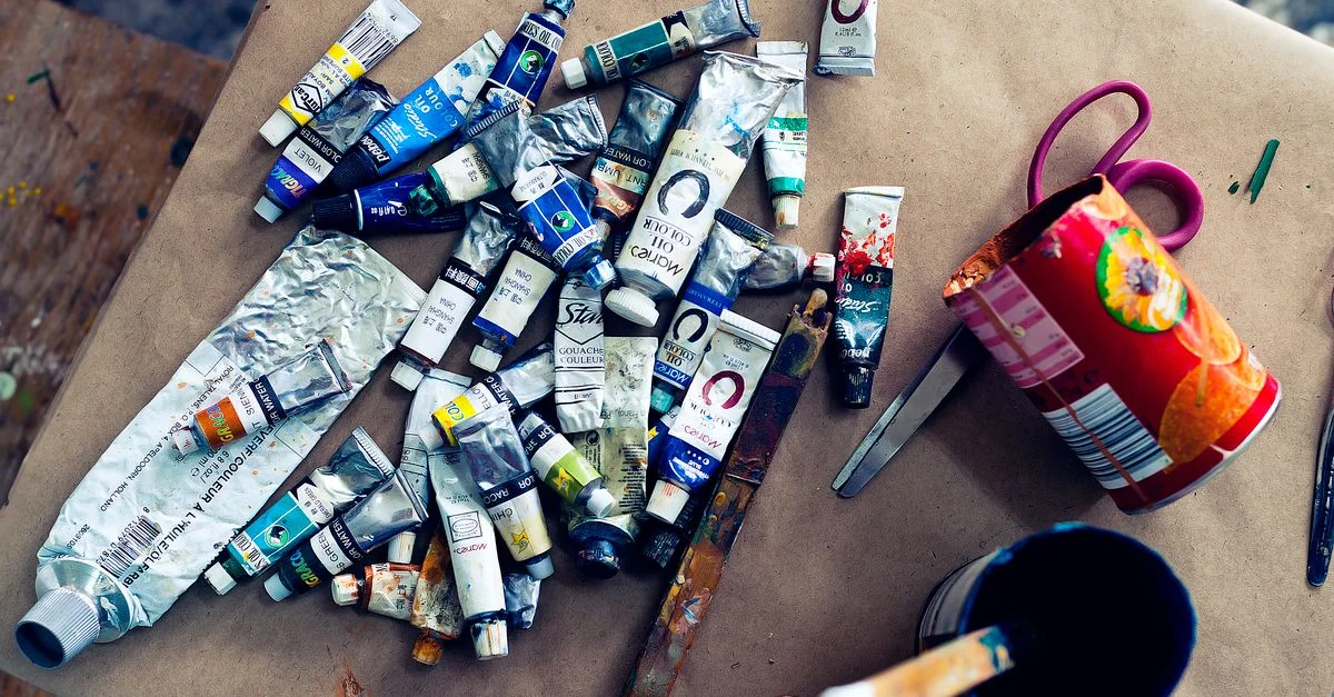 Une variété de tubes de peinture acrylique dispersés sur une table de travail dans un studio d'art.
