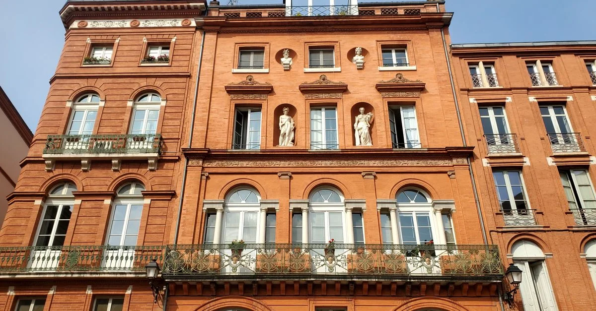 Façade en briques rouges avec une architecture classique sur la Place de la Trinité, Toulouse.