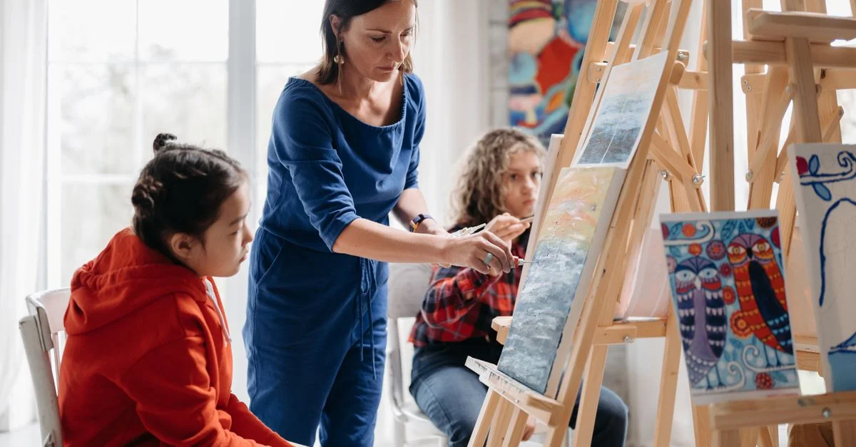 Enseignante guidant des étudiants dans un cours de peinture vibrant, se concentrant sur l'expression créative.
