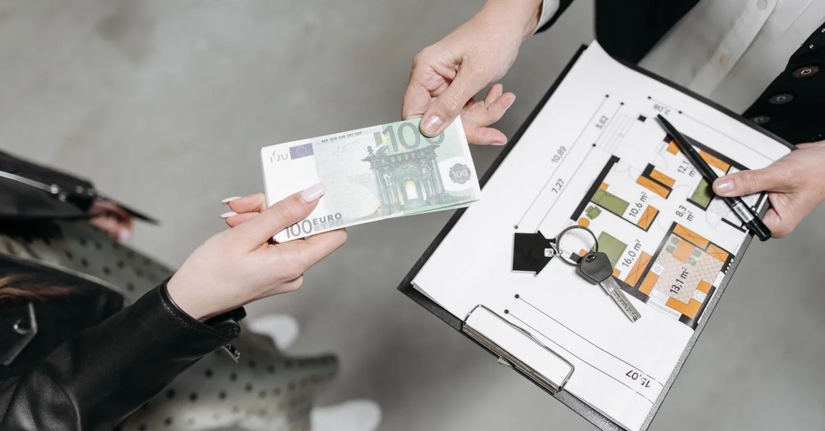 Gros plan sur une transaction immobilière avec un billet en euros, des clés et un plan de l'étage.