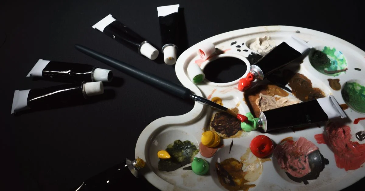 Palette d'artiste avec des tubes de peinture et des pinceaux dans un atelier créatif.
