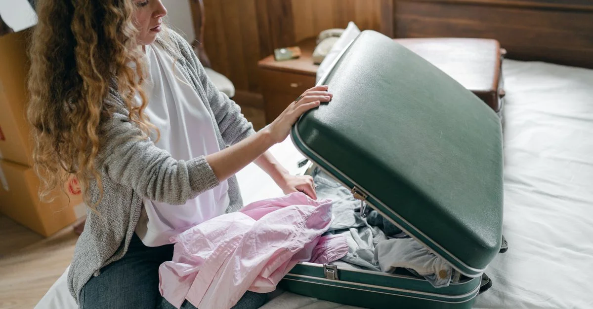 Une jeune femme fait sa valise dans une chambre, se préparant pour un voyage.